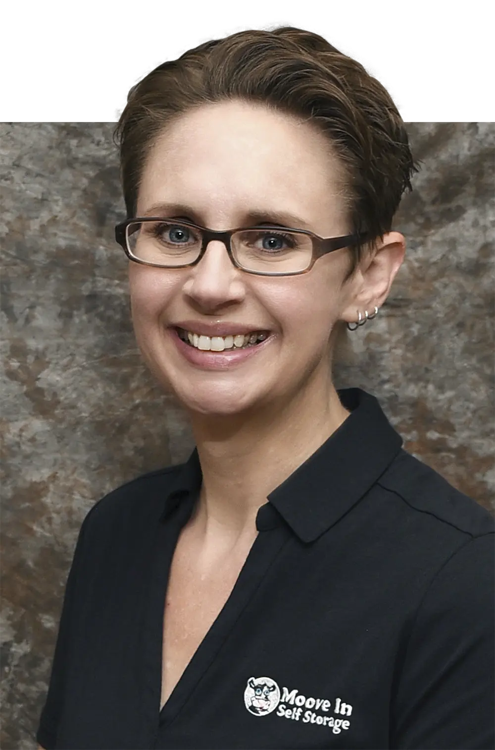 Portrait headshot photograph of Kelly Maas smiling in a black polo top shirt that shows the Moove In Self Storage logo on the polo top