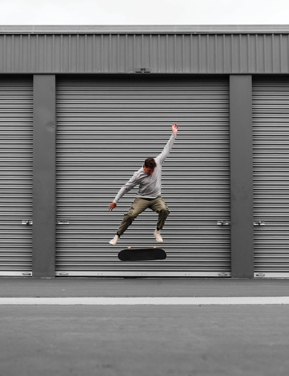 Mikey Taylor doing a flip trick on his skateboard in front of a storage unit door