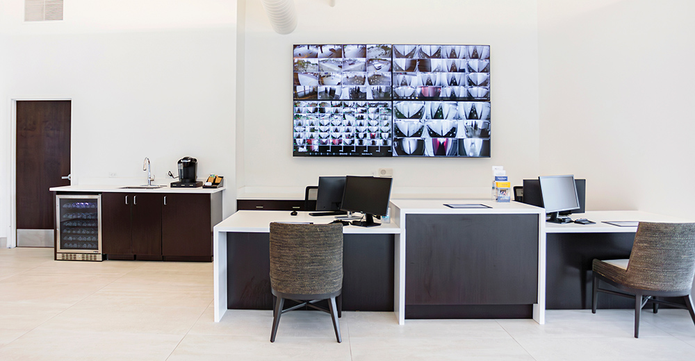 Facility's office area and security camera monitors on wall
