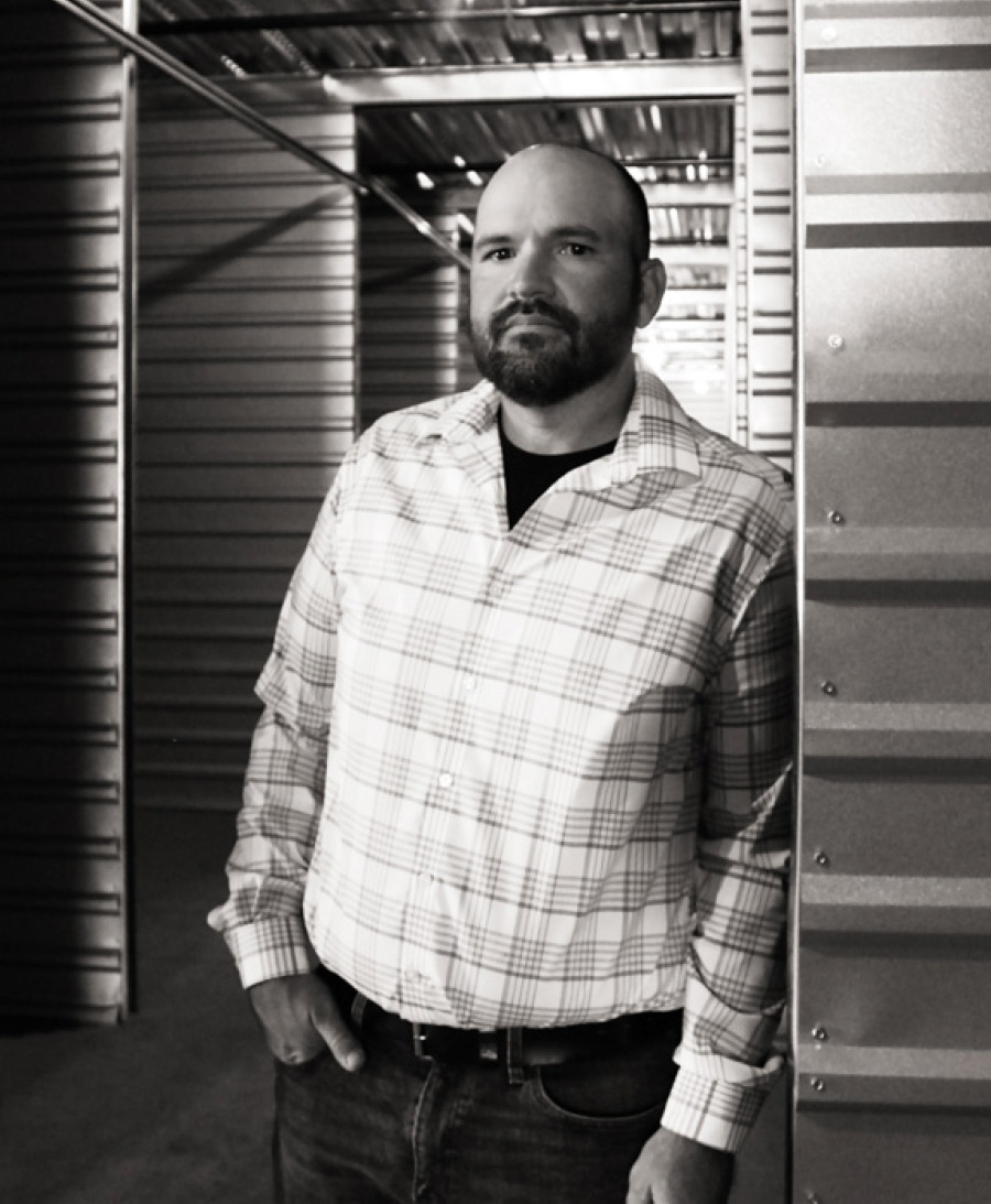 Blake Pfaff leaning against metal door with hands in pockets