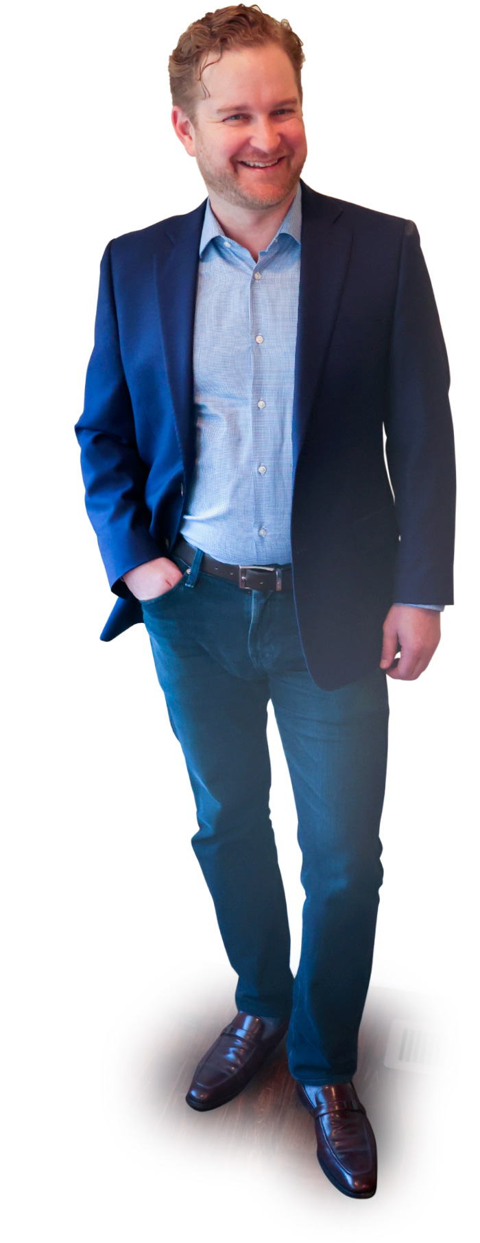 Portrait photograph of Adam Pogoda standing and smiling in a dark navy blue business blazer suit open coat and lighter faded sky blue button-up dress shirt as he has his right hand casually resting in his right jean pocket; he is also wearing dark denim blue jeans and dark brown colored dress shoes