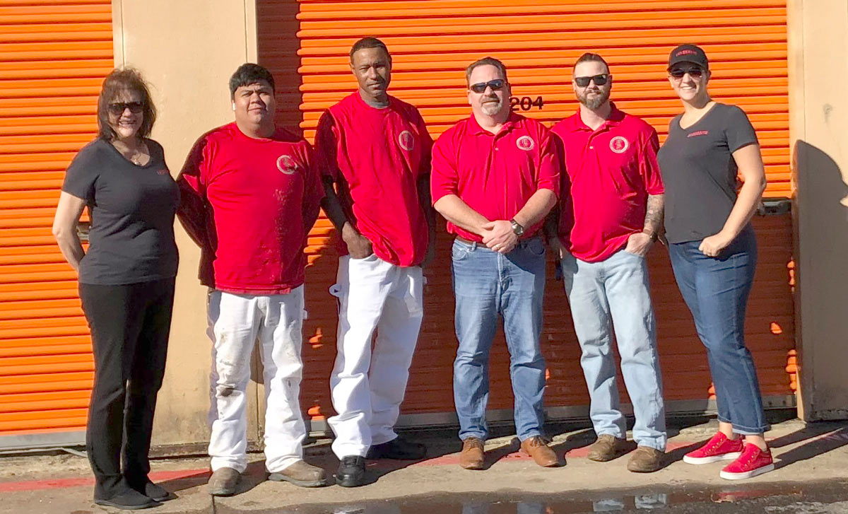 group photo of people standing in front of orange storage doors