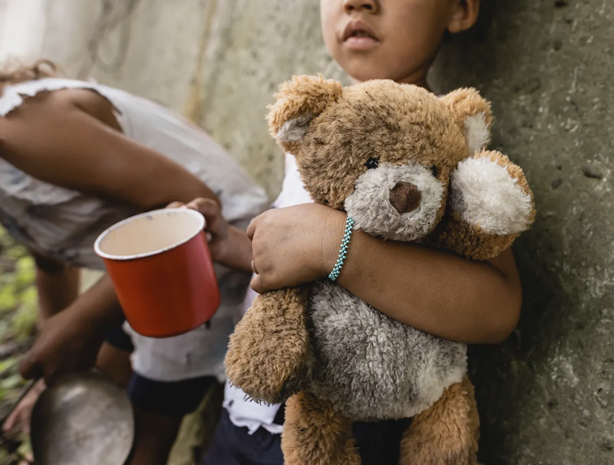 kid holding a red mug and a teddy bear
