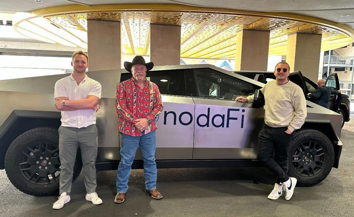 three men smiling and posing for a photo while standing in front of a vehicle 