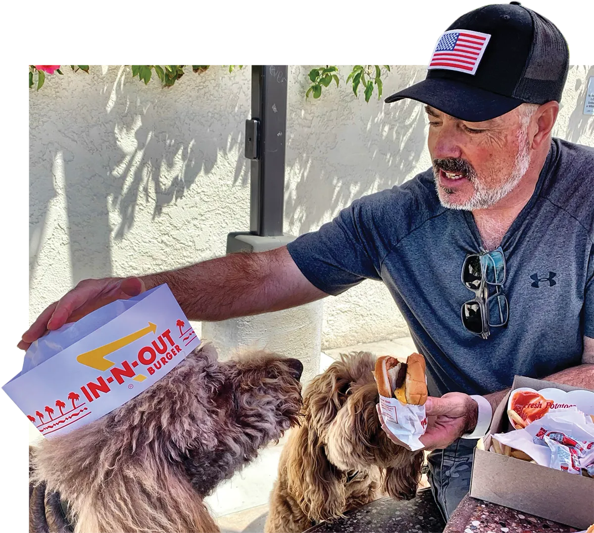 lance watkins at in n out with dogs and one is wearing an in n out hat