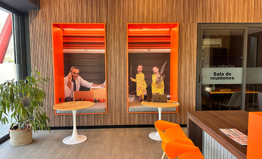 small cozy orange themed booths with tables in the lobby of a storage facility located in Latin America