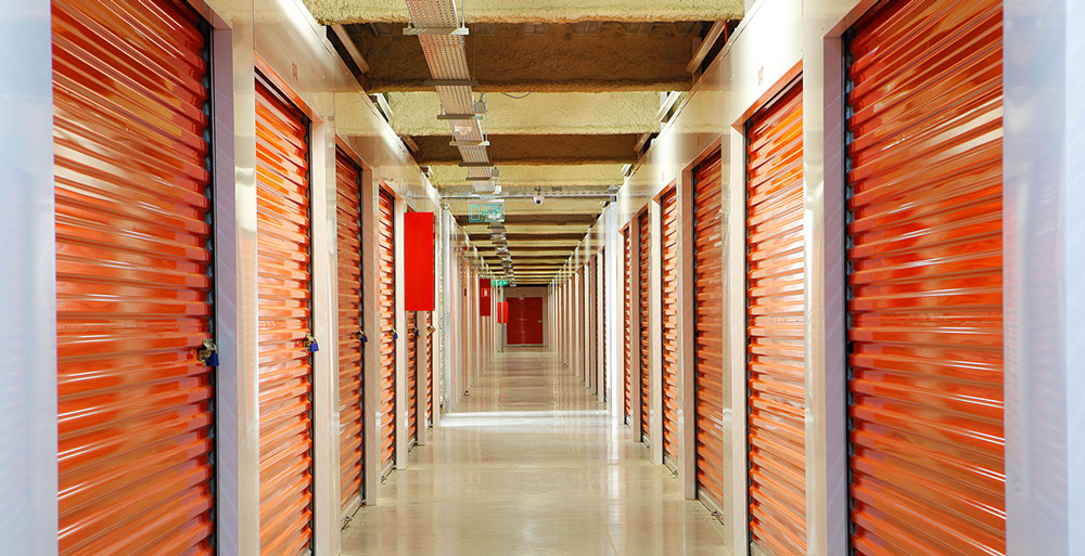 view down a long corridor of Aki KB facility lined with storage units with bright orange doors