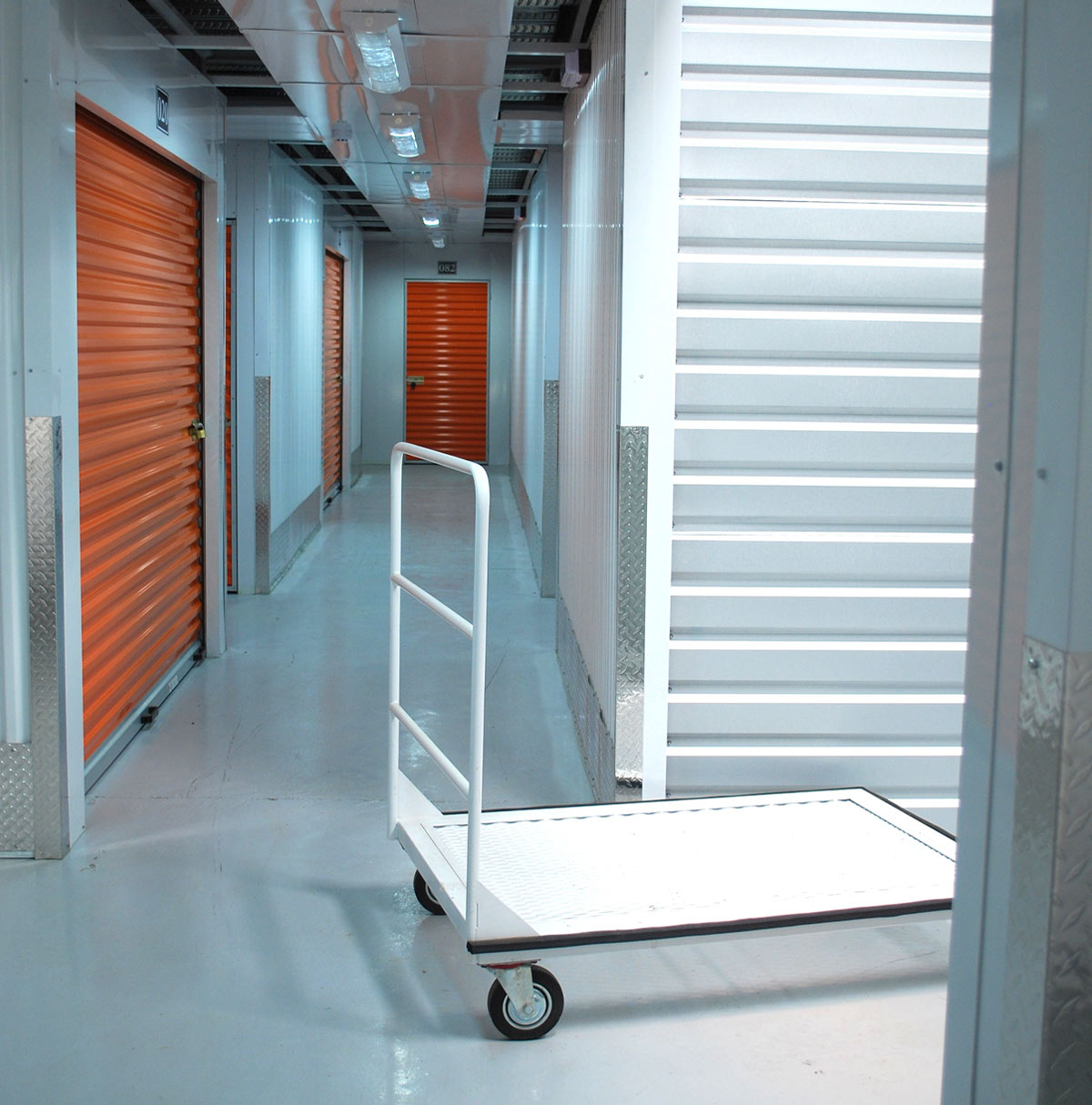 an empty cart sits in a storage unit corridor lined with orange rolling doors inside a Punta Box facility