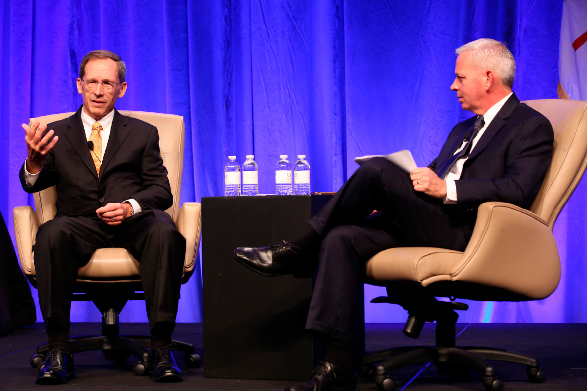 Ron Havner and Tim Dietz on stage sitting in tan chairs and speaking