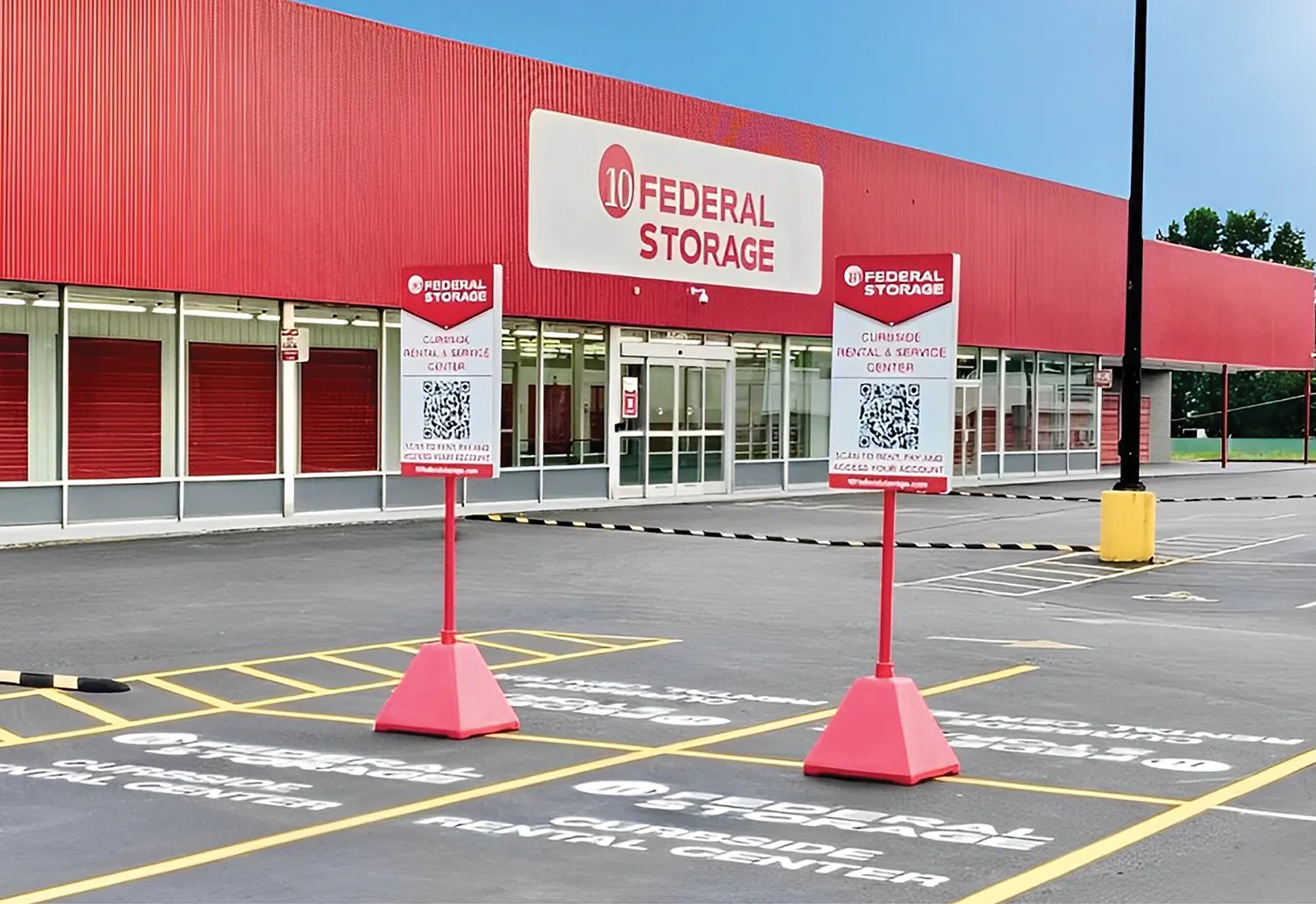 Exterior view of 10 Federal Storage facility with large red signage. Two signs for curbside rental and service center with QR codes visible in front of designated parking spaces.