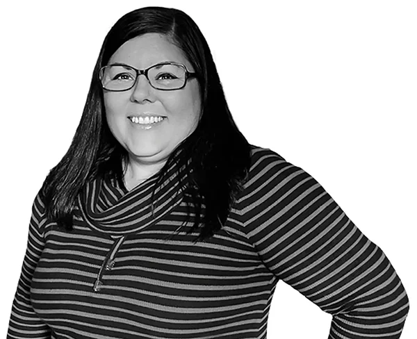 Black-and-white headshot of Erica, smiling, wearing glasses and a striped top