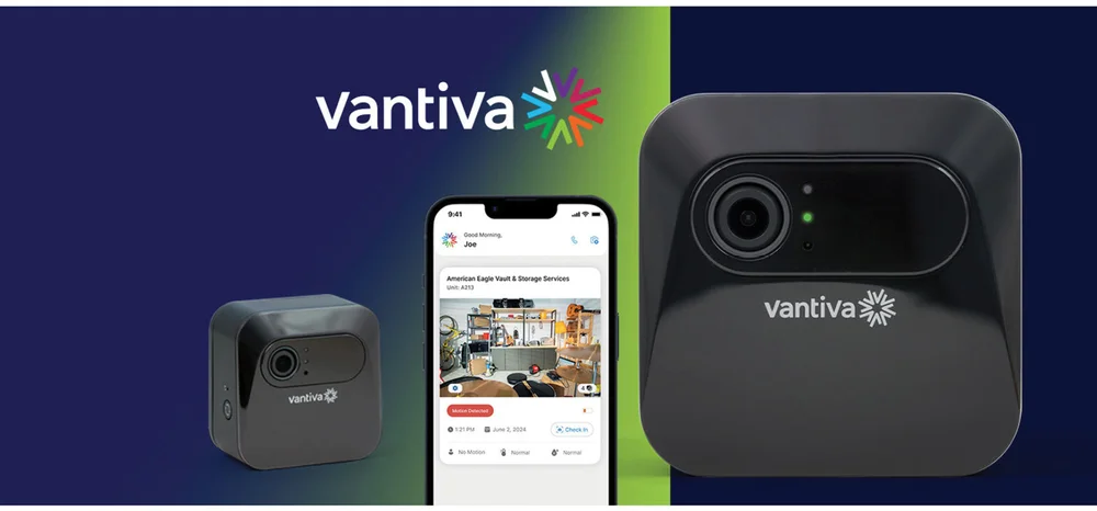 A Vantiva security camera next to a smartphone displaying a live feed from a storage facility on the app.