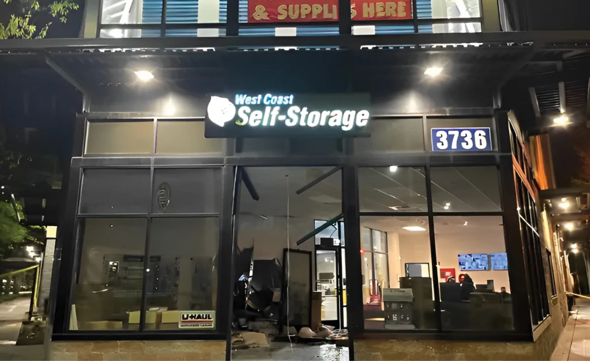 West Coast Self-Storage facility at night. The glass windows are shattered, and some interior damage is visible inside the building.