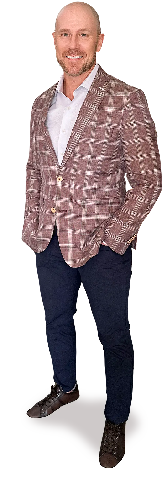 Portrait photograph of Rod Bolls standing and smiling in a light brown/white colored plaid style vertical line pattern business suit blazer and white button-up dress shirt underneath as he has his hands casually resting in his dark navy blue colored chino jean pockets; he also has on dark brown colored work shoes