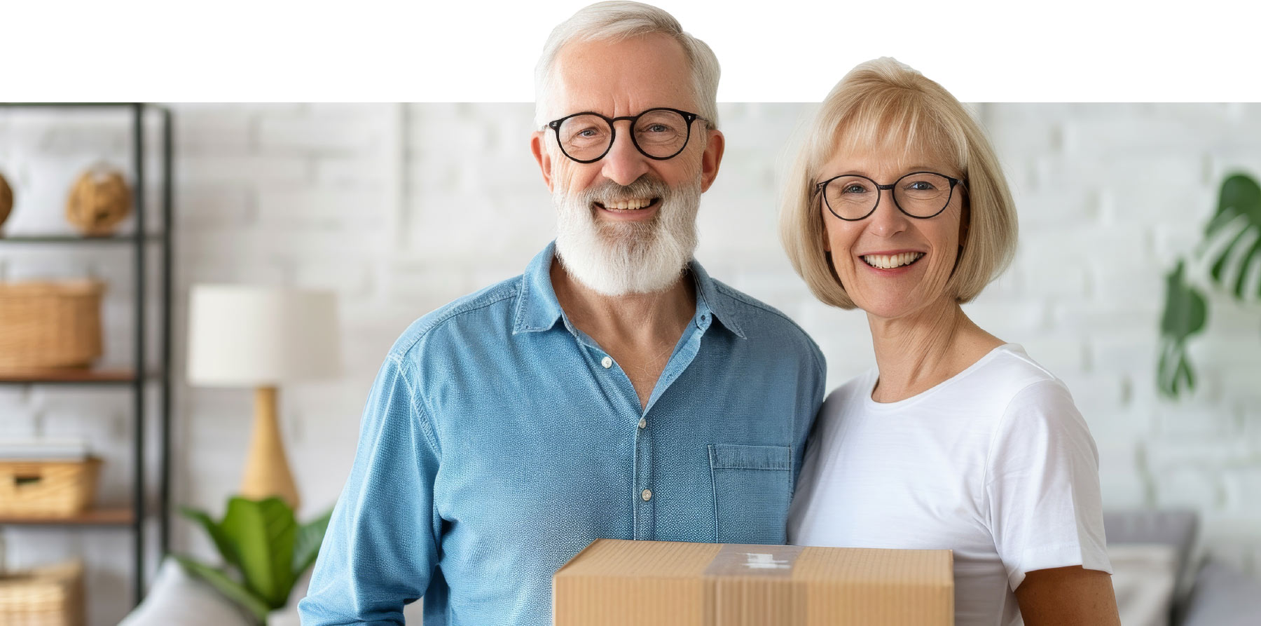 Couple smiling for photo while holding box together 