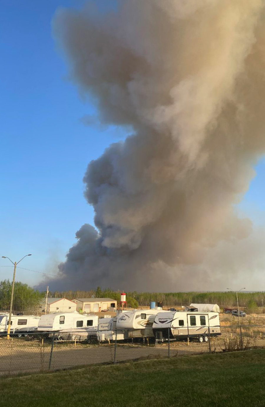 dark smoke flowing into the sky from fire near home and trailers