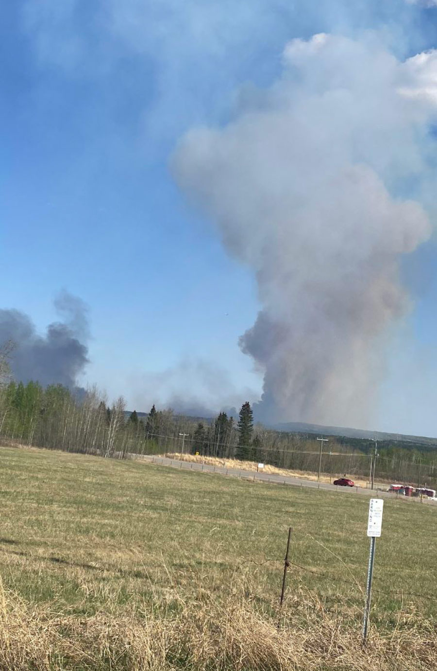 view of fire smoke from across grass field