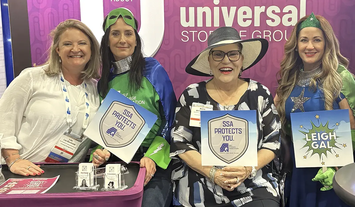 Lou Barnholdt, "Benny Fit," M. Anne Ballard, and "Leigh Gal" posing together at a booth