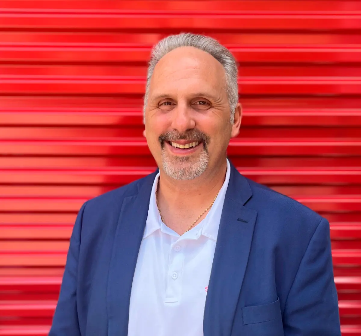 Portrait headshot photograph close-up view of Mark Cieri smiling in a dark navy blue business blazer suit and white polo top t-shirt