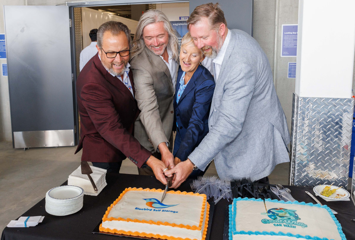 Bluebird Self Storage team members cutting a company-branded cake