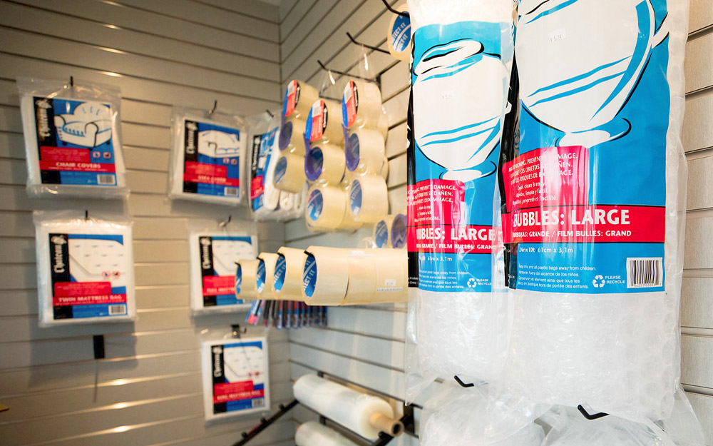 close up of the bubble wrap, furniture and mattress covers, tape, and other supplies hanging from a storage lobby wall