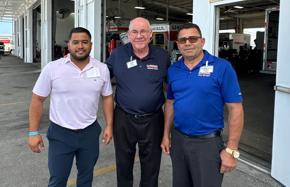 Orismel Alvarez, Joe Shoen, Gullermo Blanco take a group photo in front of U-Haul garage