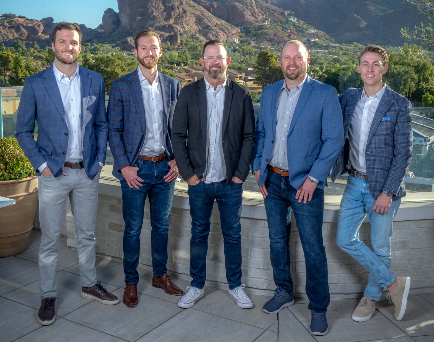 David Brown, Tanner Bryson, Dave King, Jake Nolte, and Jimmy Wentworth standing in jeans and various blue blazers with mountainous landscape behind them