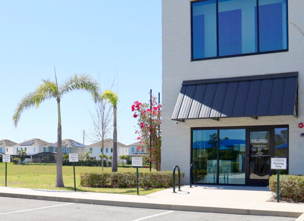 A modern, white two-story building with large windows and a dark awning over the entrance.