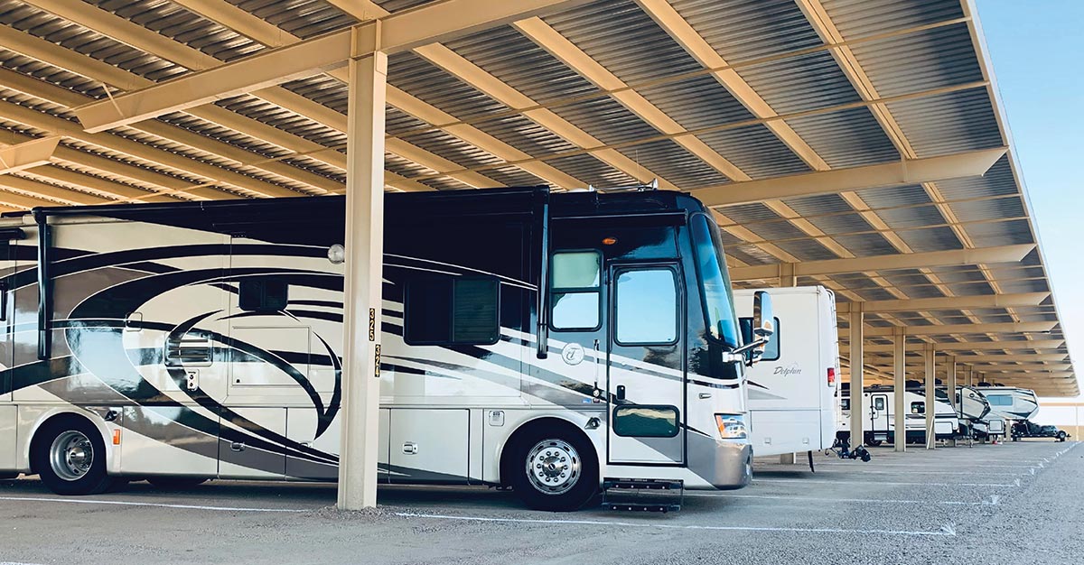 A row of RVs parked under a large metal canopy.
