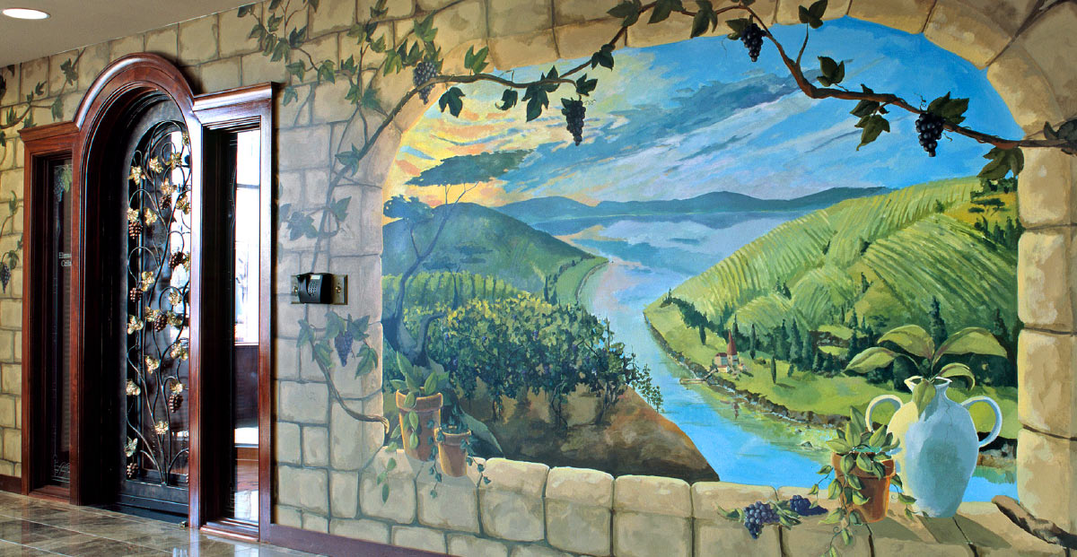wall mural depicting a vineyard landscape with a river or lake winding through rolling hills, all viewed through a painted stone archway