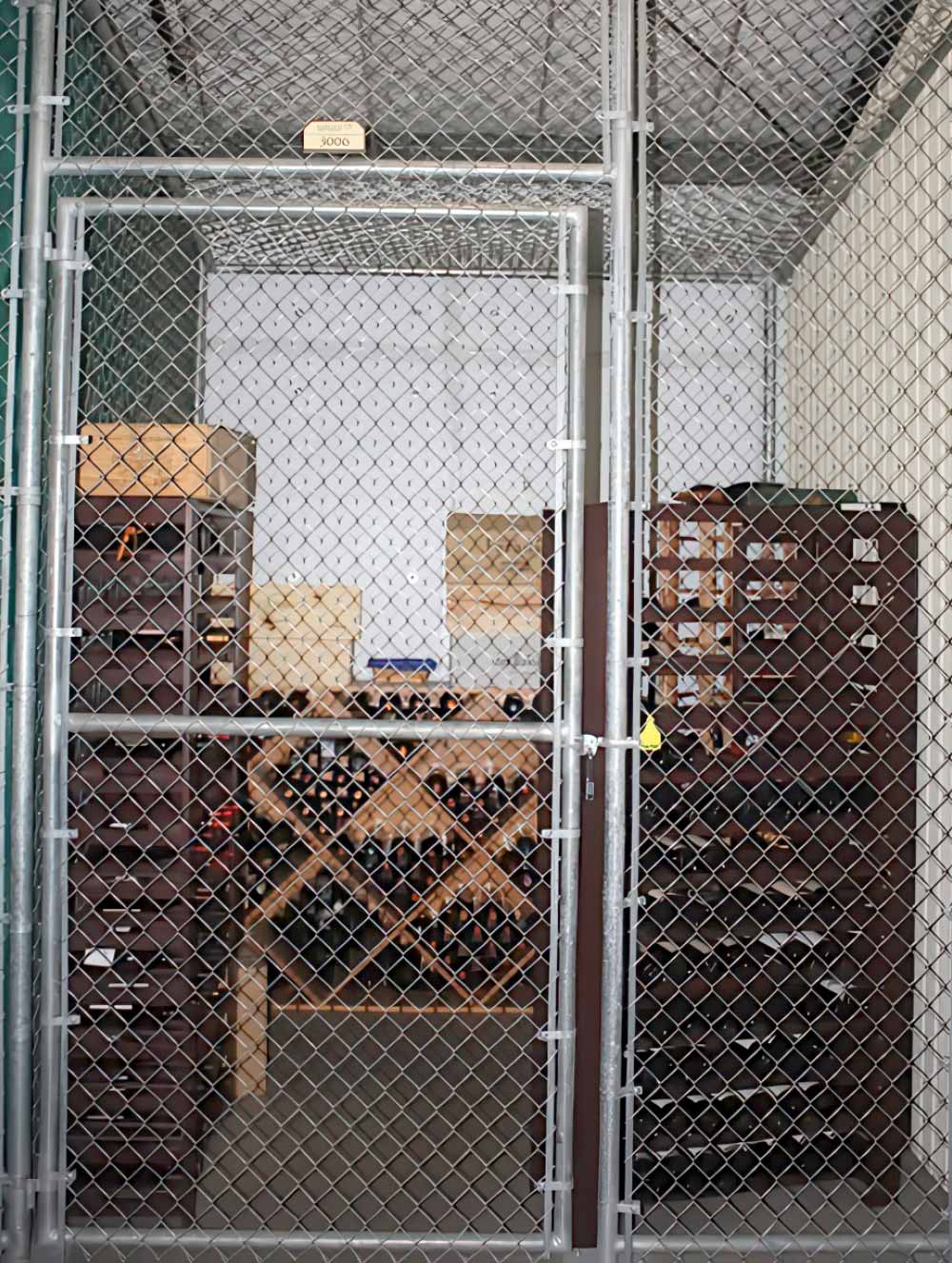a locked chain-link fence door, revealing a wine storage area inside