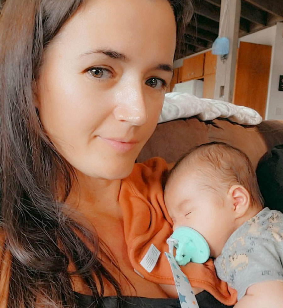 Close-up of Alonna Ross looking at the camera while cradling her newborn grandson, Kai, in a tender moment.