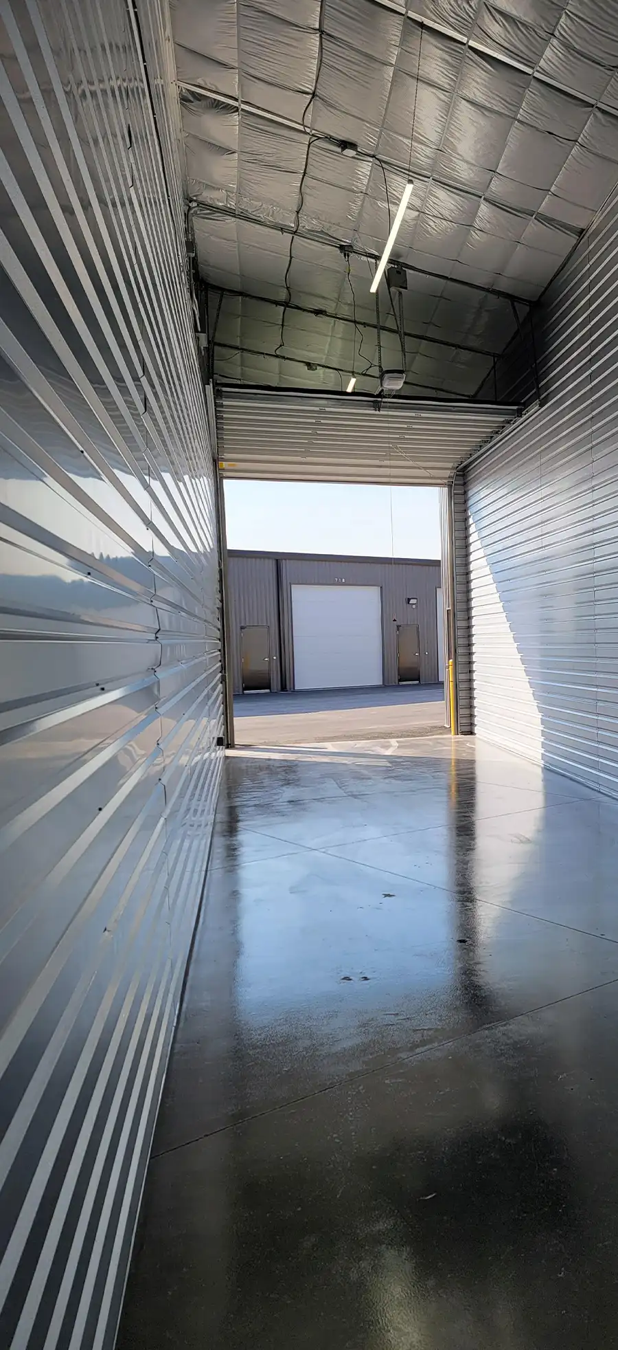 Interior view of a spacious, clean drive-up storage unit at Missoula Storage City, looking out towards other buildings.