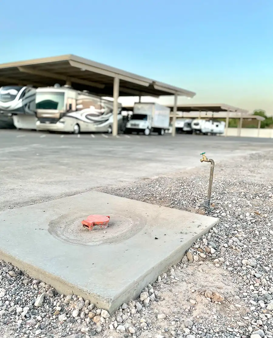 RV storage facility at Ameripark Covered Storage, showing covered parking spaces and utility hookups on a gravel lot.