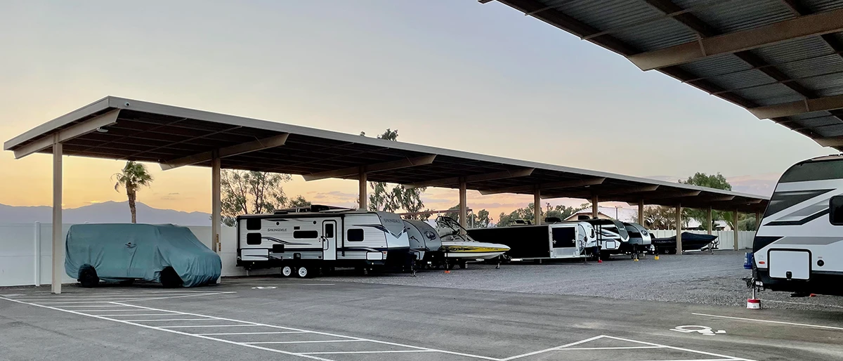 Wide view of canopy storage at an Ameripark Covered Storage facility in Arizona, showing various RVs, trailers, and boats parked under protective roofs.