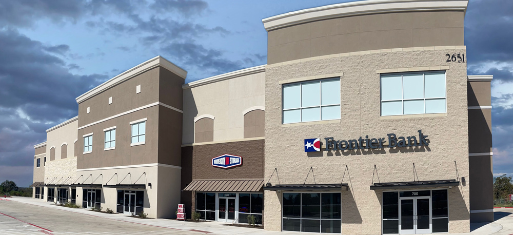 A modern commercial building housing a bank and storage company, with large windows and a parking area.