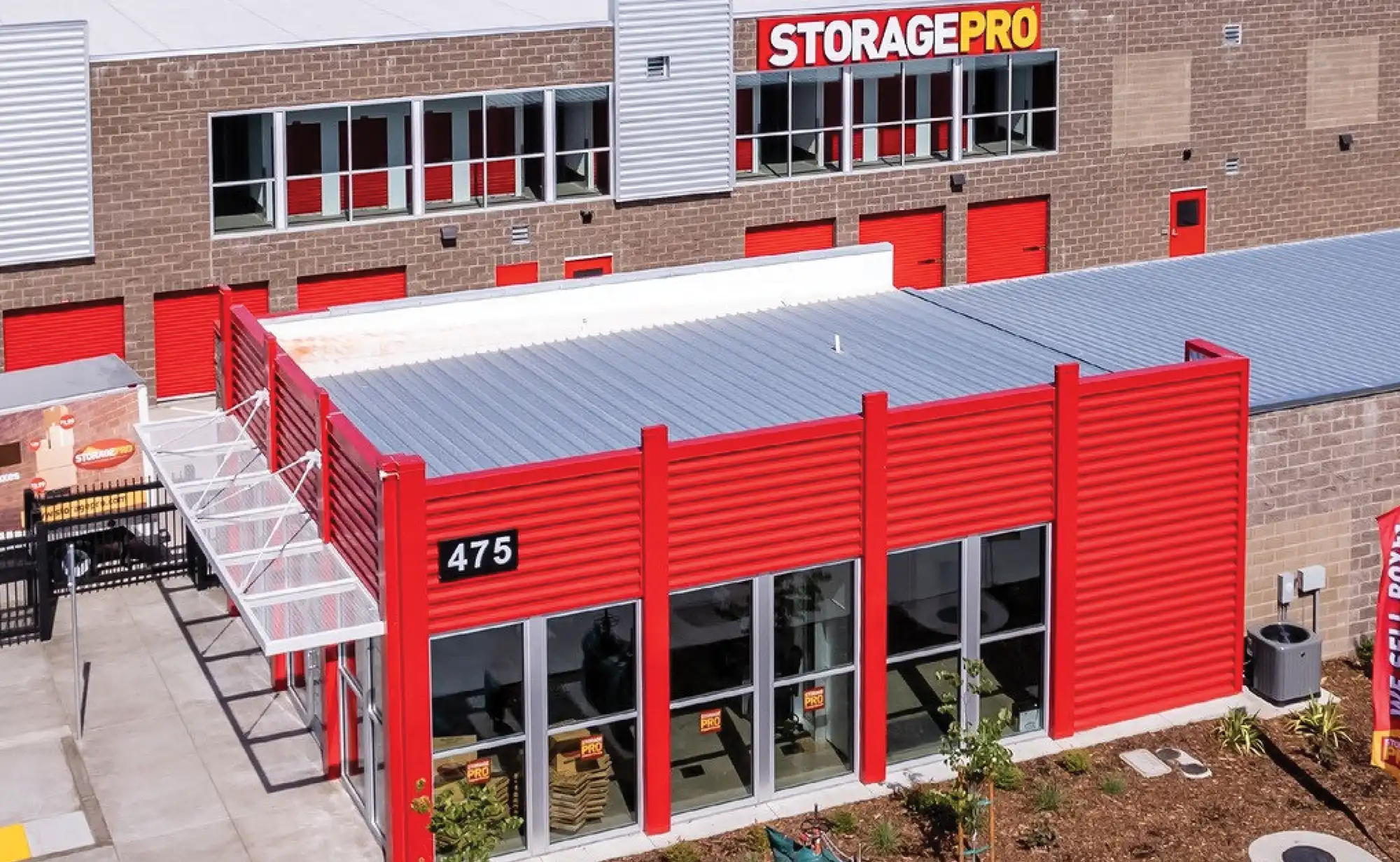 Storage facility with red panels, large glass windows, and "STORAGE PRO" sign.
