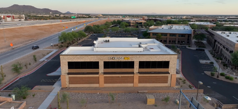 An aerial photograph of a Storage365 facility, showing its two-story, tan and brown brick building from above.