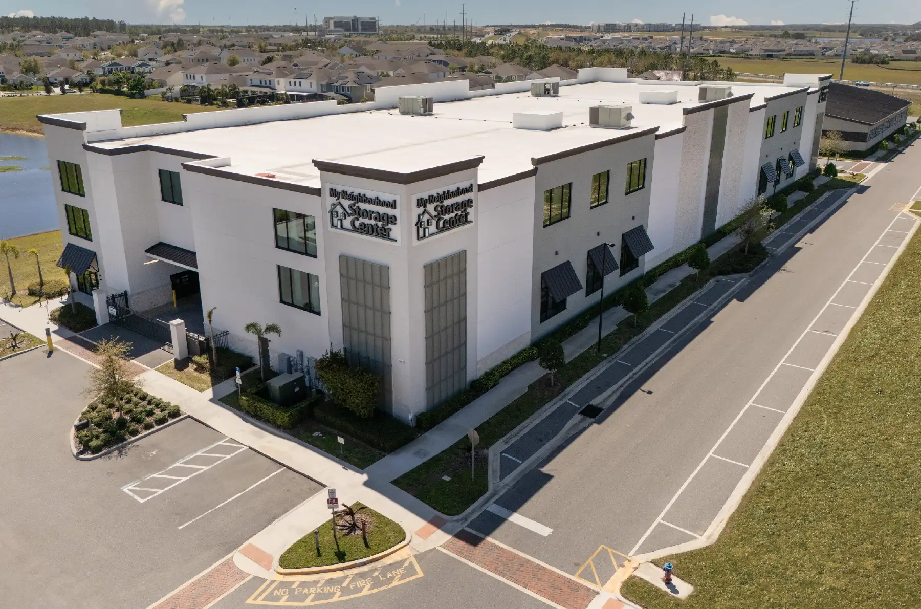 An aerial, oblique view of a modern, multi-story self-storage facility named "My Neighborhood Storage Center."