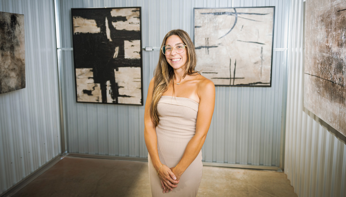 one of the female artist smiling in front of artwork