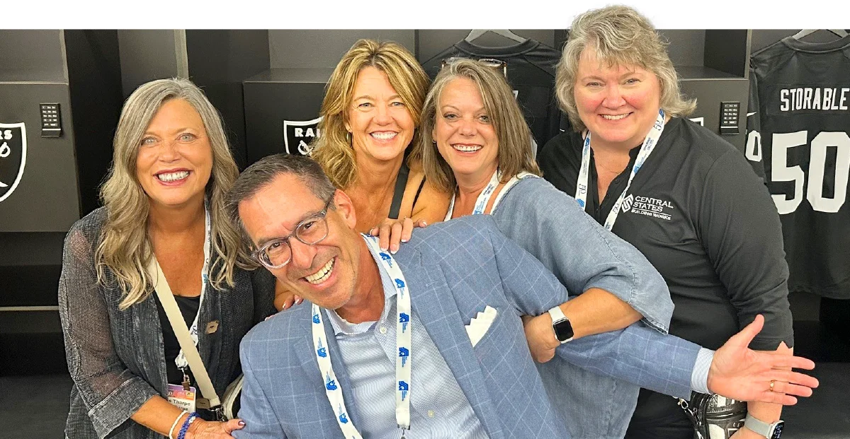 Five business professionals posing excitedly at a trade show