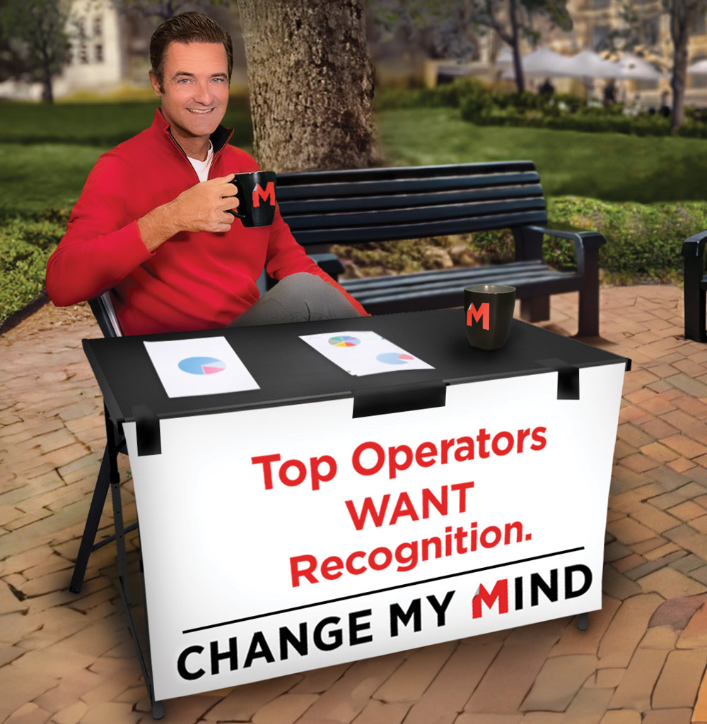 A man in a red sweater holds a mug at a table with charts and a sign that reads "Top Operators WANT Recognition. Change my mind."