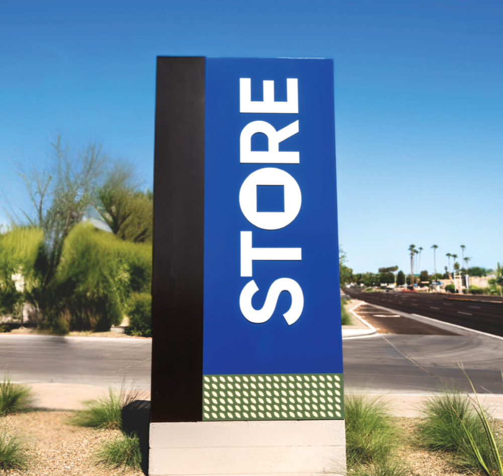 A tall sign saying "STORE" stands beside a road under a clear sky.
