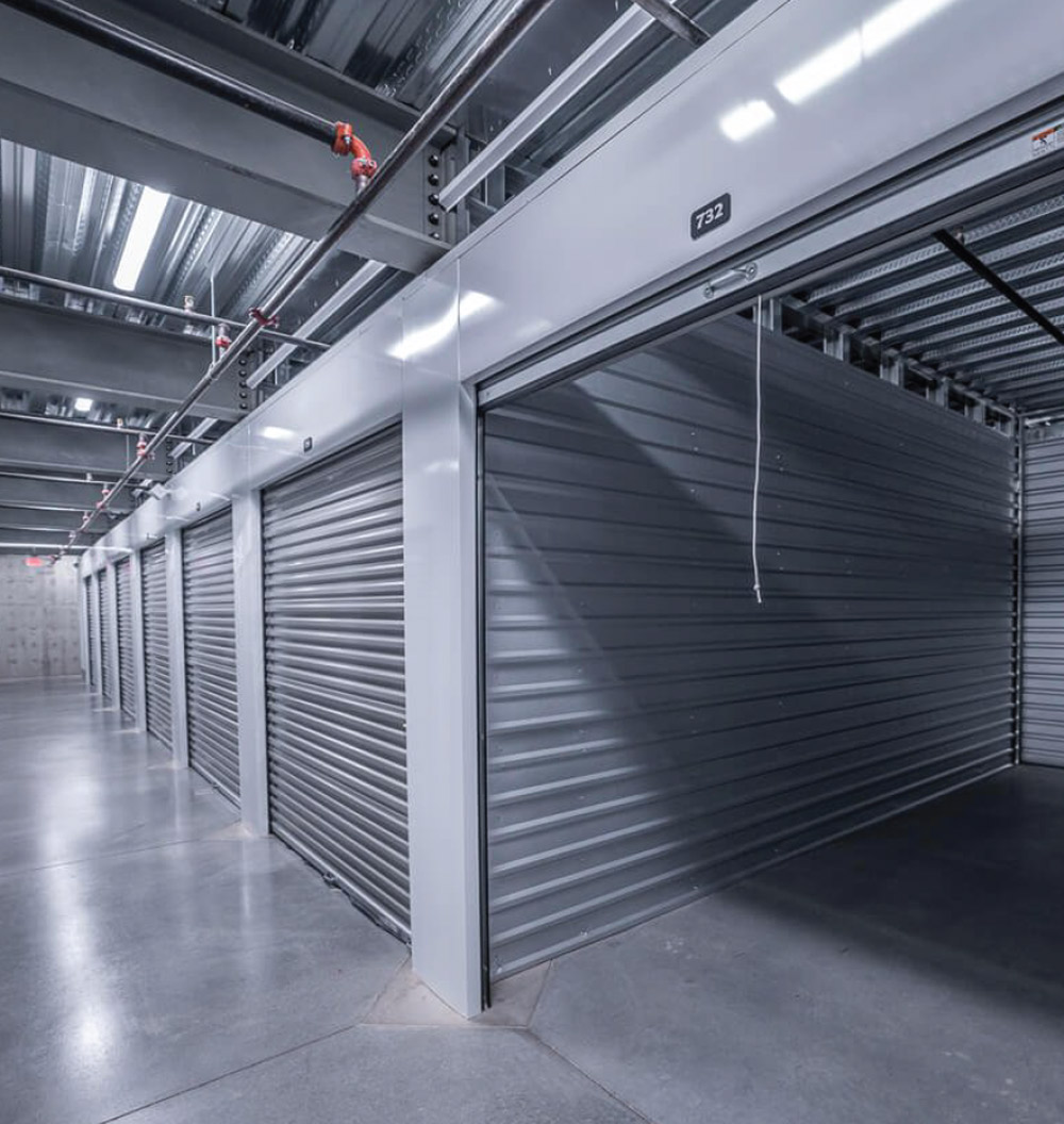 Interior of a storage facility with metal storage units and concrete floors.