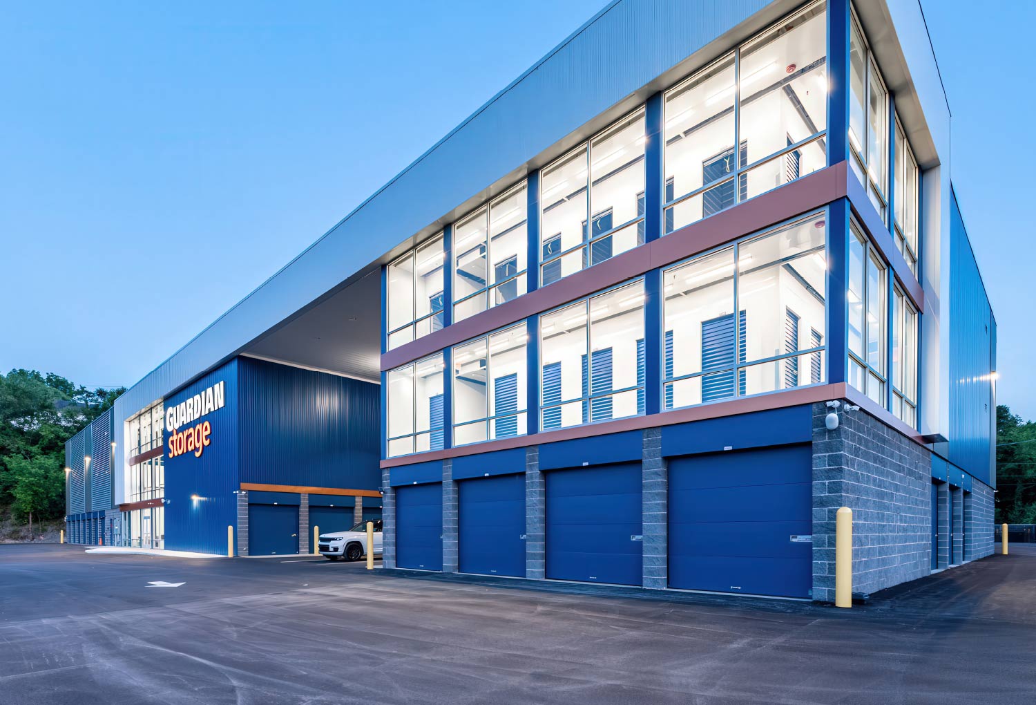 Exterior of a large, modern, blue and gray Guardian Storage facility at dusk.