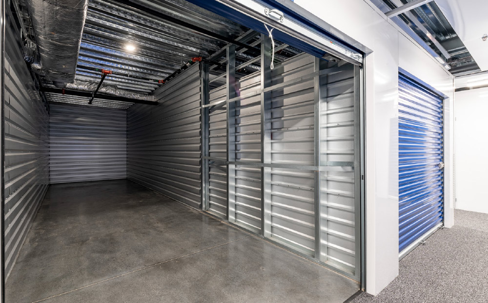 Interior of a clean, empty self-storage unit with a concrete floor and metal walls.