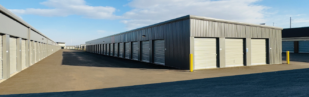 Long rows of outdoor drive-up storage units with light gray doors and dark gray siding.