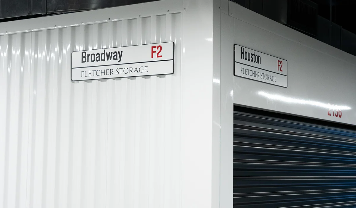 Fletcher Storage facility corner with directional signs for Broadway and Houston, marking different storage unit areas.