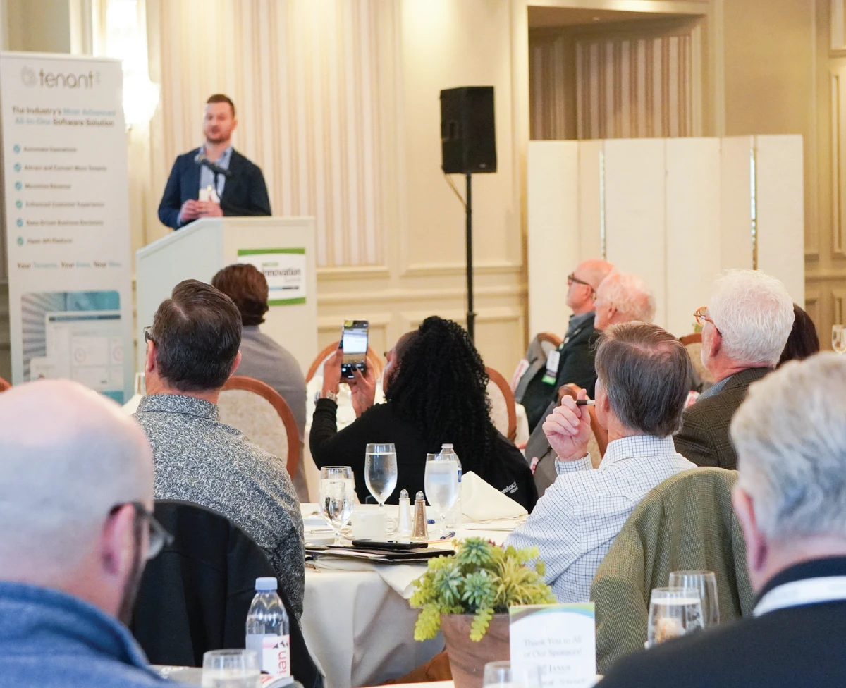 A male speaker presenting at the Tenant Inc. Innovation Summit to an audience of self-storage industry professionals.
