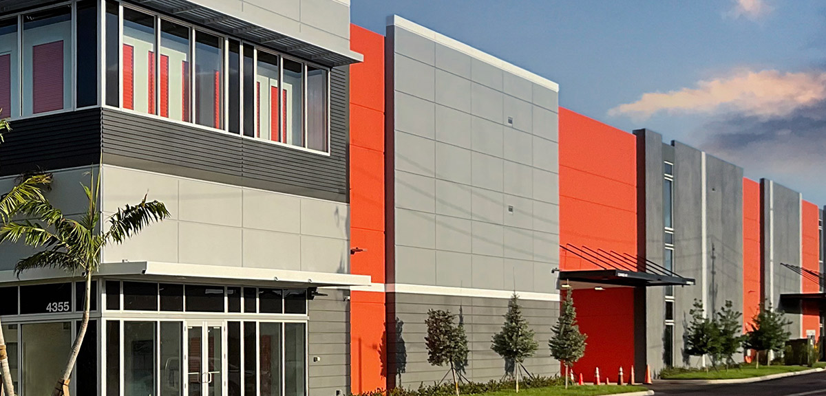 Wide-angle exterior shot of a large storage facility featuring a combination of gray, orange, and dark metal panels.
